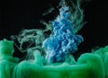 close-up view of abstract green and blue flowing paint on black